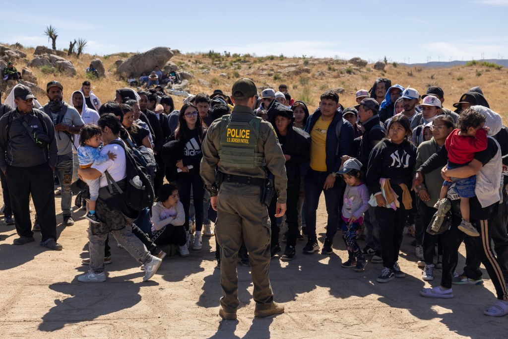 A lone border agent stands before dozens of migrants who crossed into Jacumba Hot Springs, California.