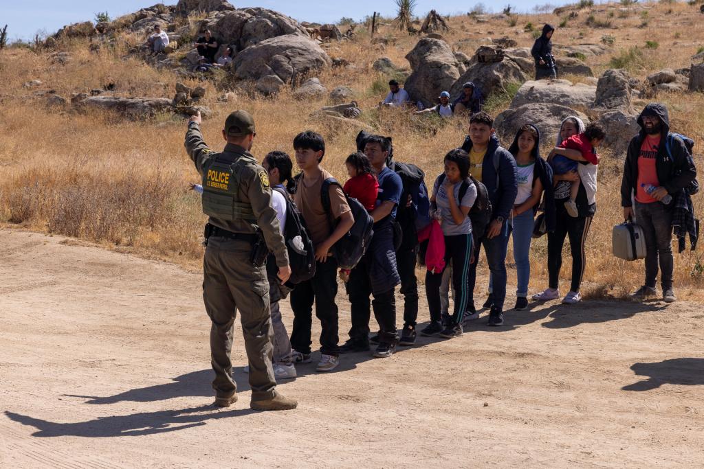 Migrants arrive in Jacumba Hot Springs, California and are lined up by a lone Border Patrol agent taking them into custody.