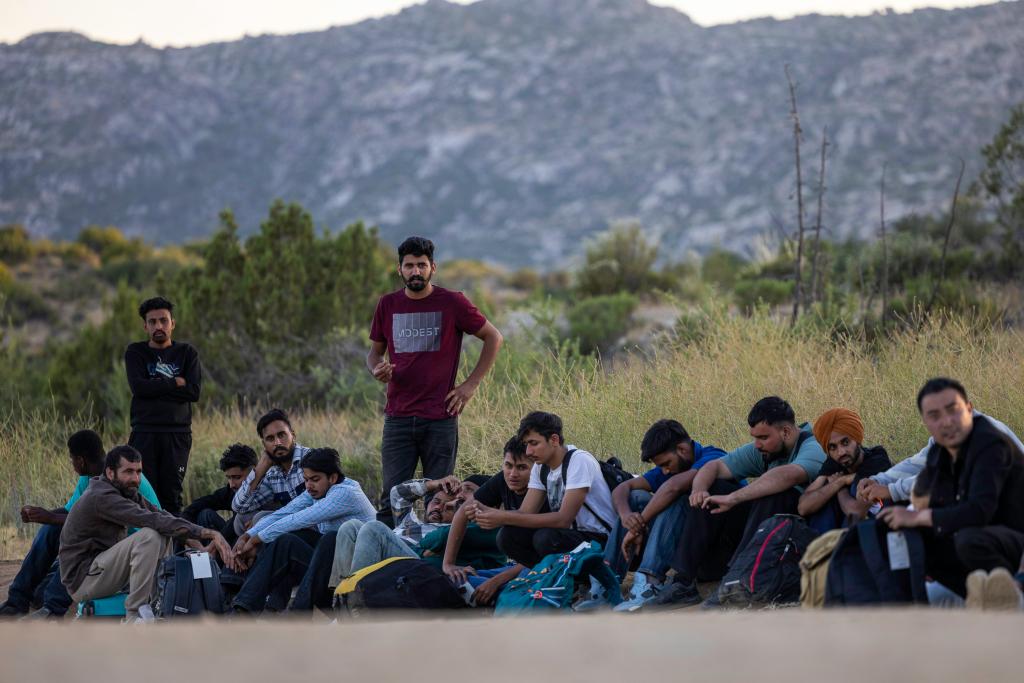 Dozens of migrants from across the globe wait in the remote area of Jacumba Hot Springs, California, after crossing the border for Border Patrol.
