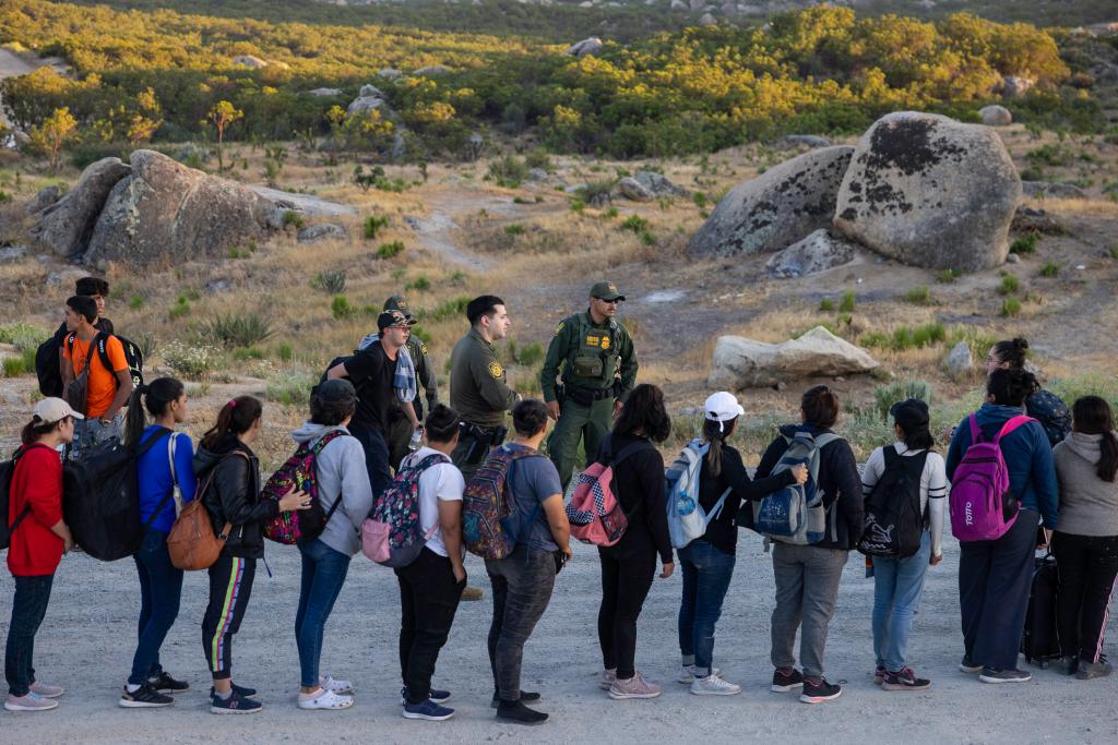 Migrants stand in line as Border Patrol agents take them in for processing in the San Diego border sector.