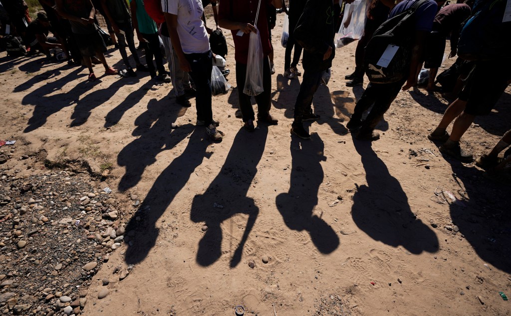 Migrants wait at the border in Eagle Pass, Texas, for federal authorities to take them into custody.