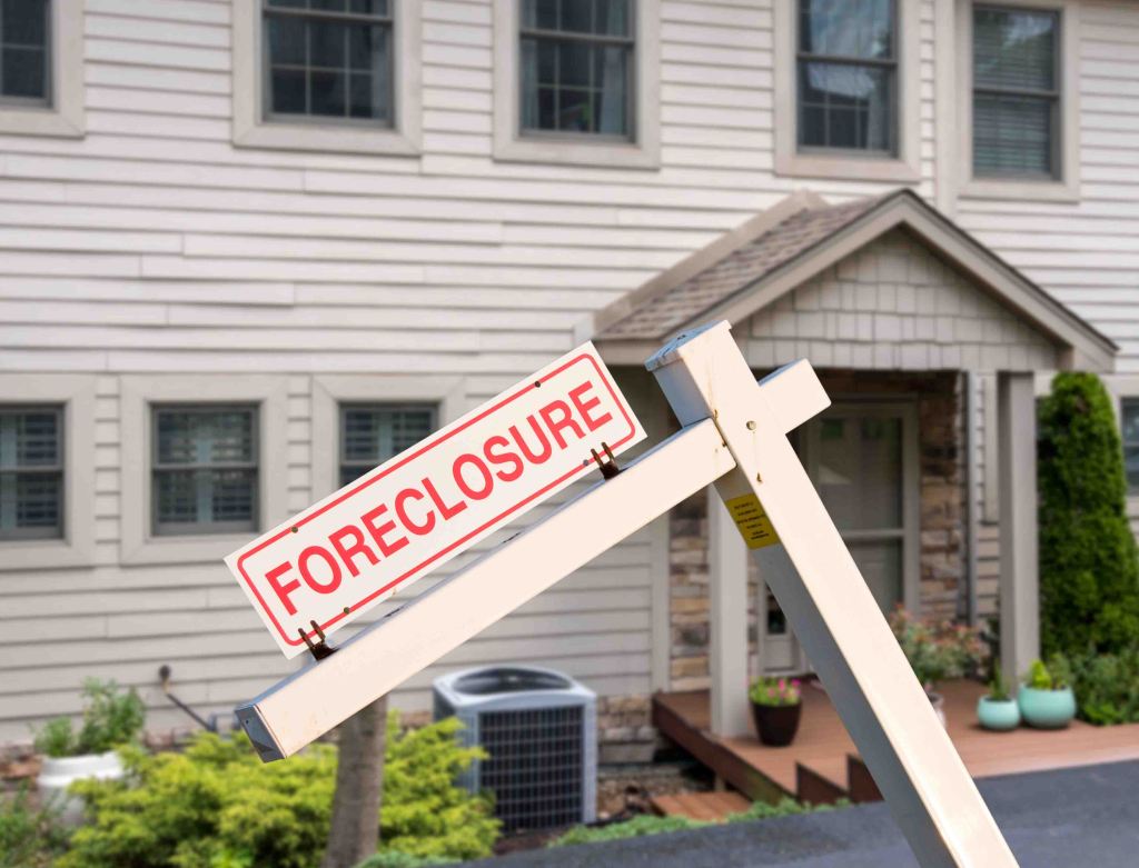 Mockup foreclosure sign placed in front of a modern townhome illustrating the impact of recession and pandemic