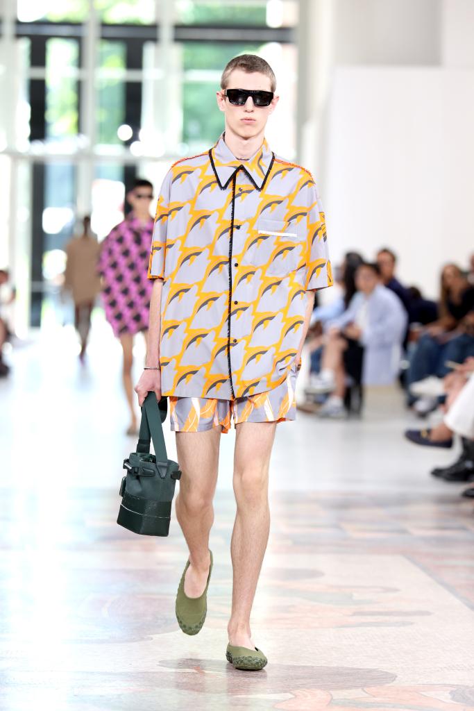 Model walking down the runway at the Gucci Men's Spring Summer 2025 Fashion Show in Milan, wearing a colorful shirt and short shorts