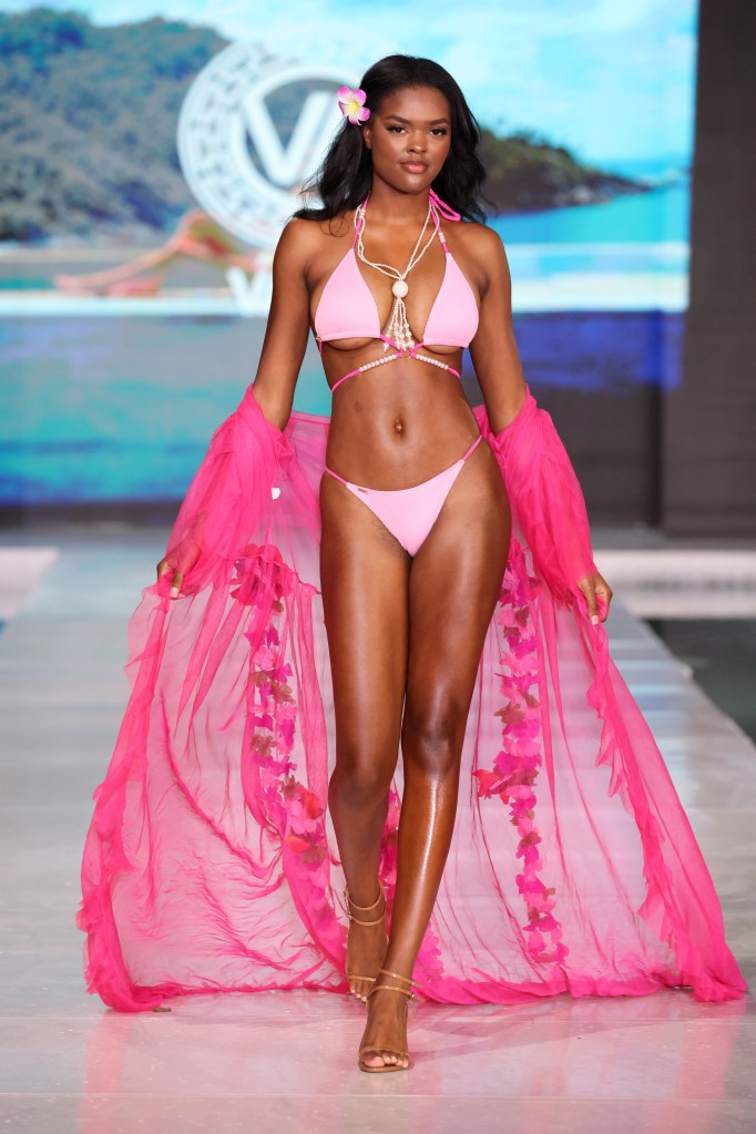 A model in a pink garment and cape walking down the runway for Vaida during Miami Swim Week at SLS South Beach, Miami, Florida.