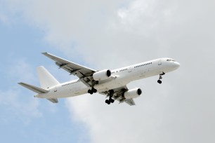 Modern unmarked white passenger jet flying in the sky