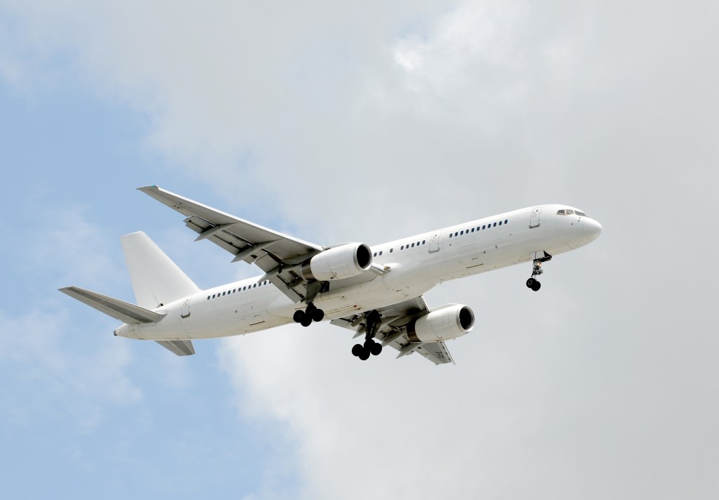 Modern unmarked white passenger jet flying in the sky
