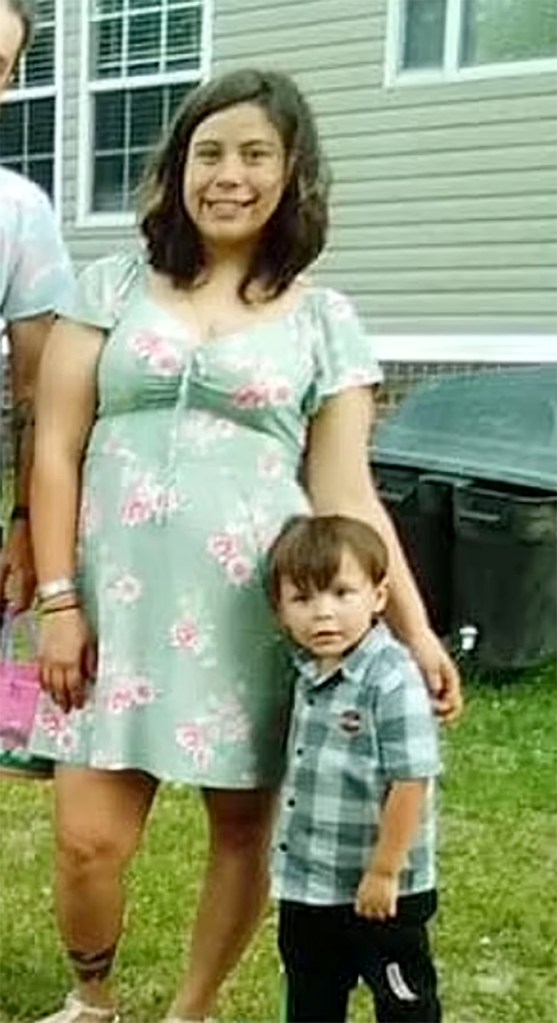 Leilan Simon wears a floral dress and poses with her arm around her son Quinton, in a picture taken outside a house