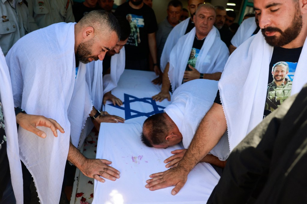 Mourners cry over the coffin of one of eight IDF soldiers killed in Gaza last Sunday. 
