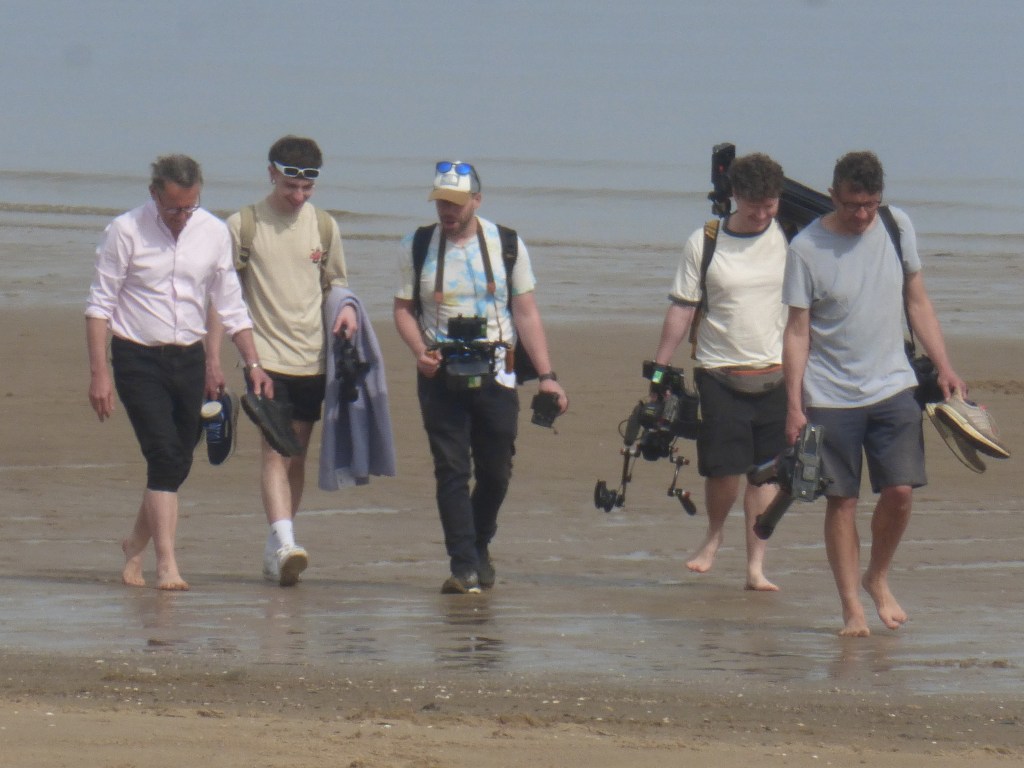 TV presenter Michael Mosley with wife Clare, two women and a camera crew at Colwyn Bay beach, North Wales, weeks before his disappearance