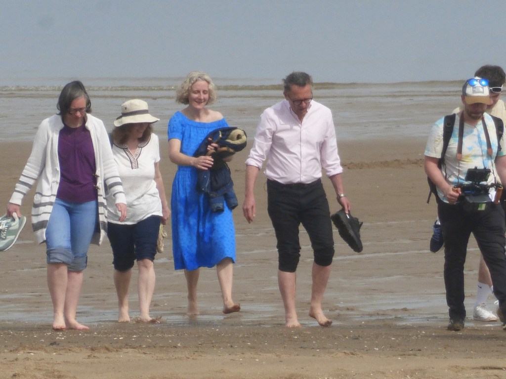 Michael Mosley with wife Clare and others, including a camera crew, at Colwyn Bay beach, north Wales, weeks prior to his disappearance