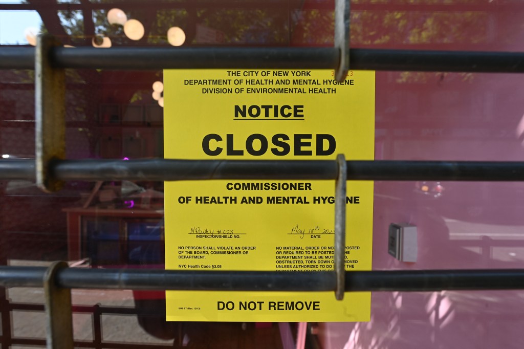 A yellow "Closed" notice on an unlicensed pot shop, close-up. 