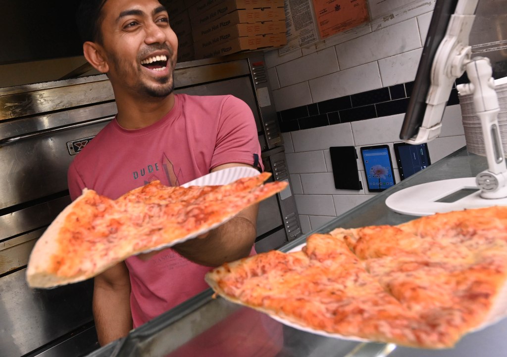 Worker Monowar Townhid, 27, with pizza at the 99 Cents Pizza shop on East 14th Street and Second Avenue in the East Village. 