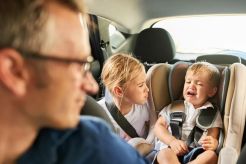 man turned around looking at little kids in backseat of car