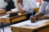 Students taking exam in classroom. Education test and literacy concept. Cropped shot, hand detail.