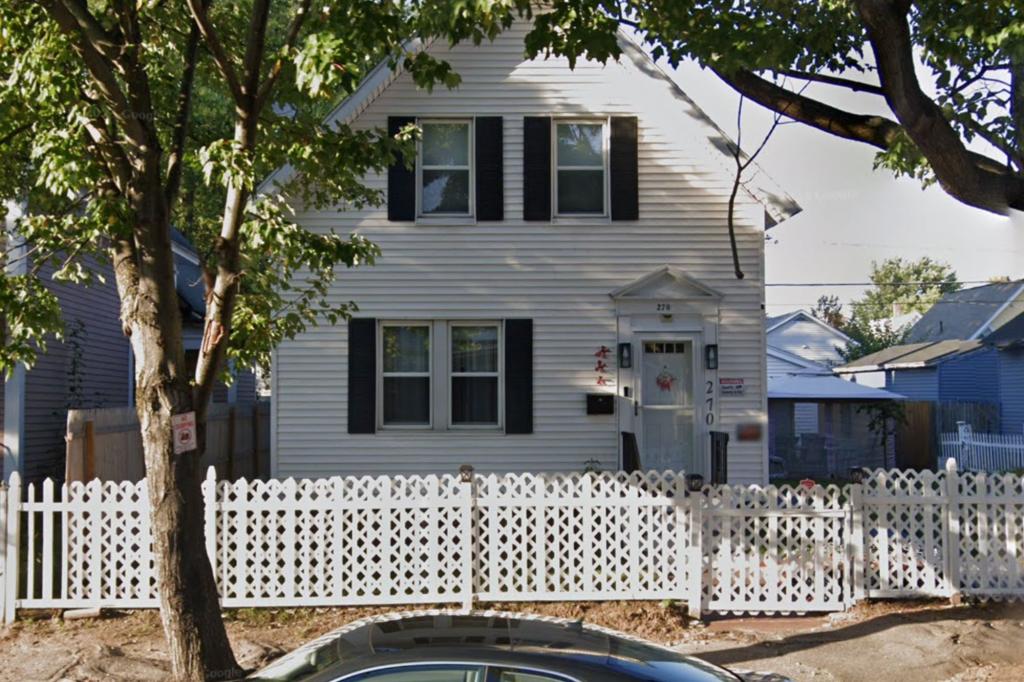 White house with black shutters and a white fence