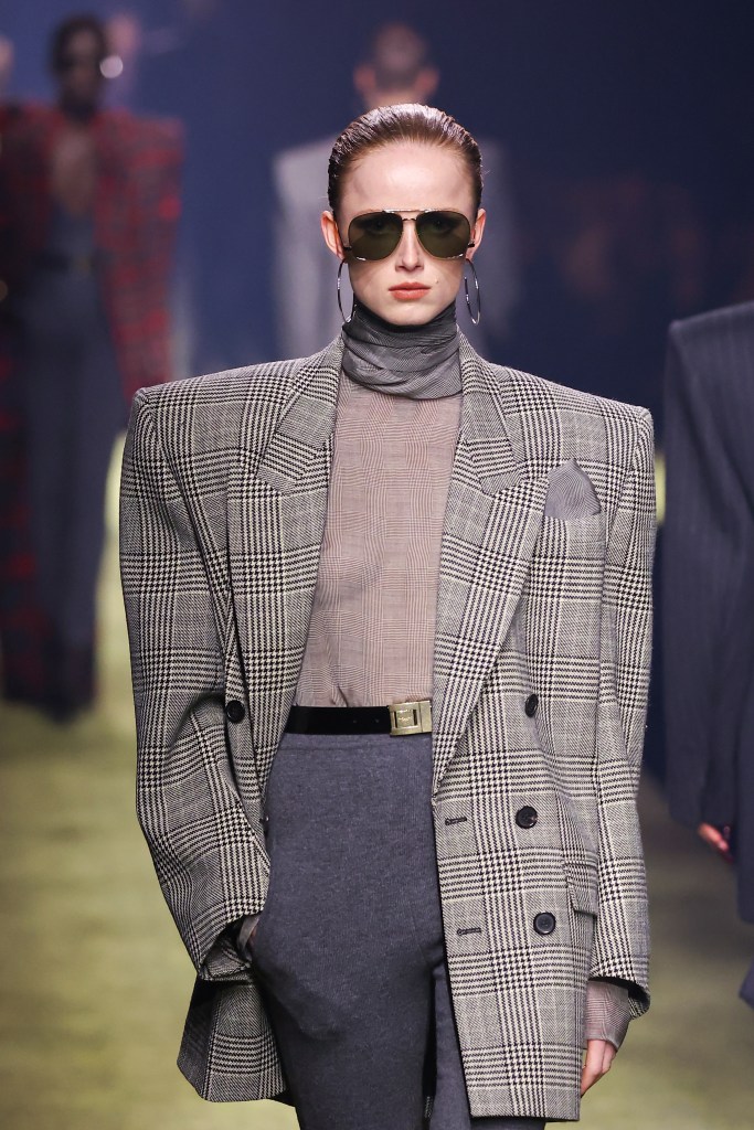 A model wearing sunglasses and a jacket showcasing a pocketed garment on the runway at the Saint Laurent Womenswear Fall Winter 2023-2024 Paris Fashion Week show.