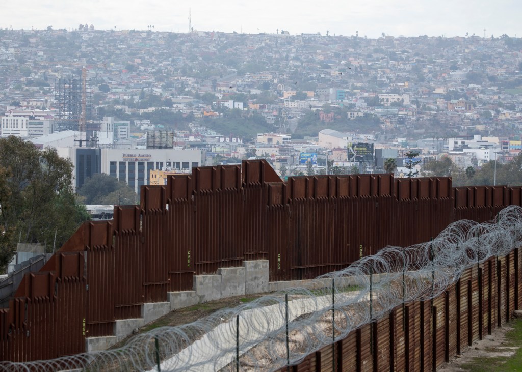 An old border wall fence sits parallel to the newly constructed 30 foot wall near San Diego, California.