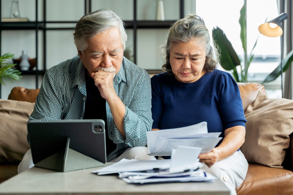 couple paying bills on tablet and holding papers