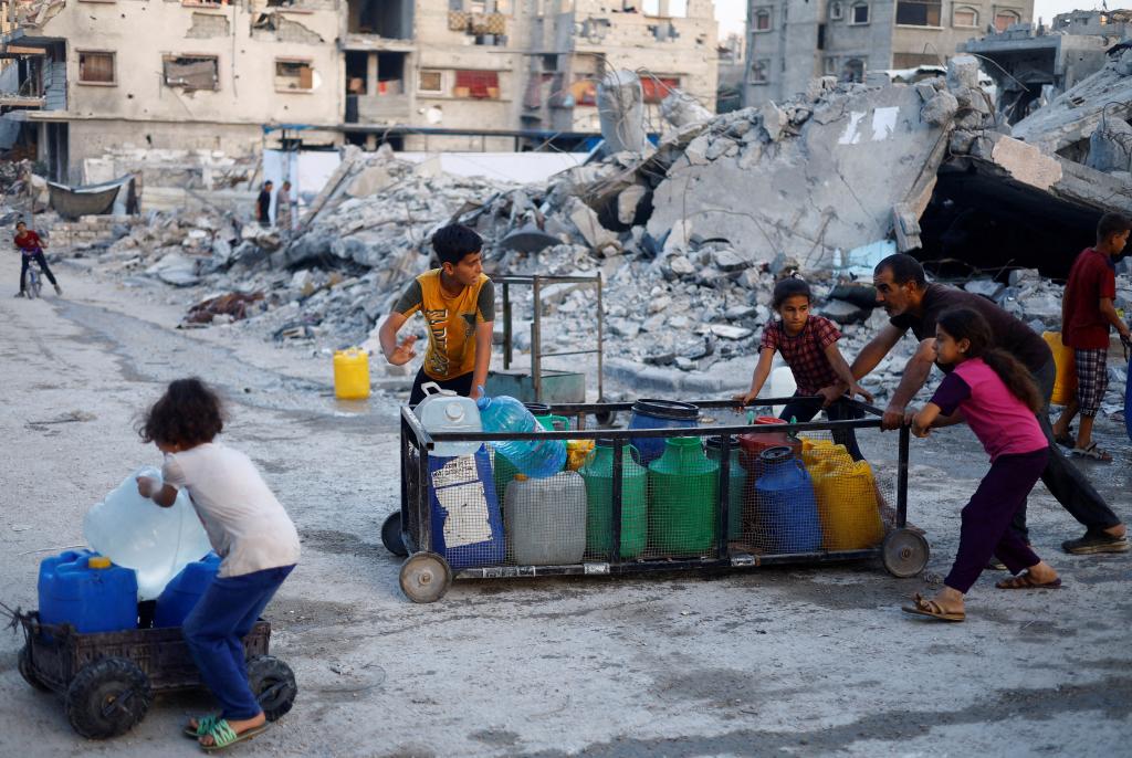 A Palestinian man and children push a cart with water containers in southern Gaza City on Monday.