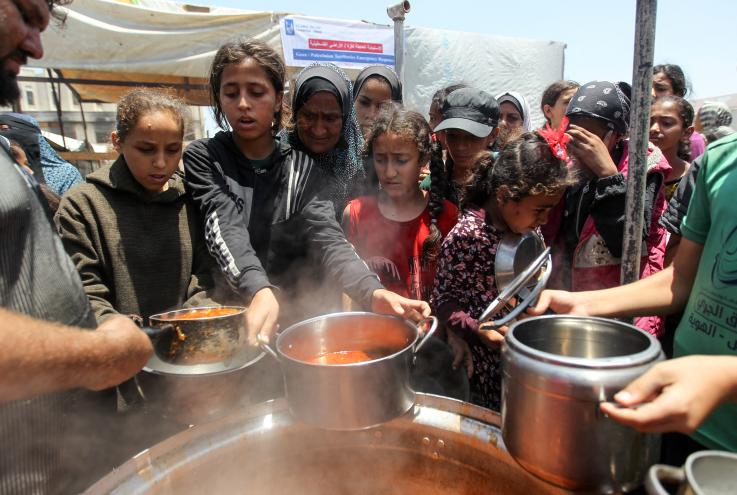 Palestinians receiving food cooked by a charity kitchen in Khan Younis on June 19, 2024.