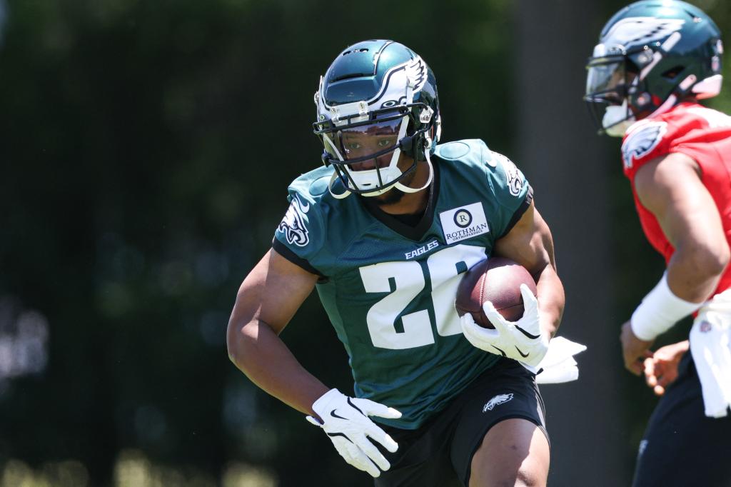 Philadelphia Eagles running back, Saquon Barkley, holding a football and running during practice at the NovaCare Complex.
