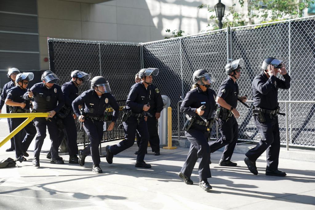 Police officers run to control the protesters gathered outside the theater in Los Angeles on Saturday.