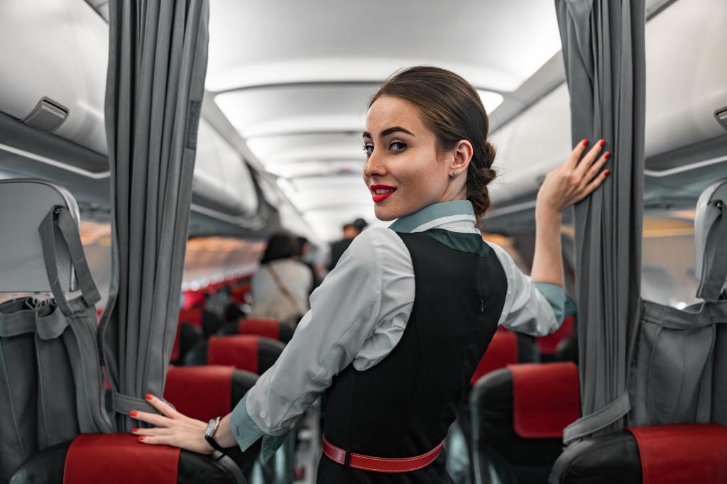 Caucasian female flight attendant in uniform welcoming passengers on an airplane