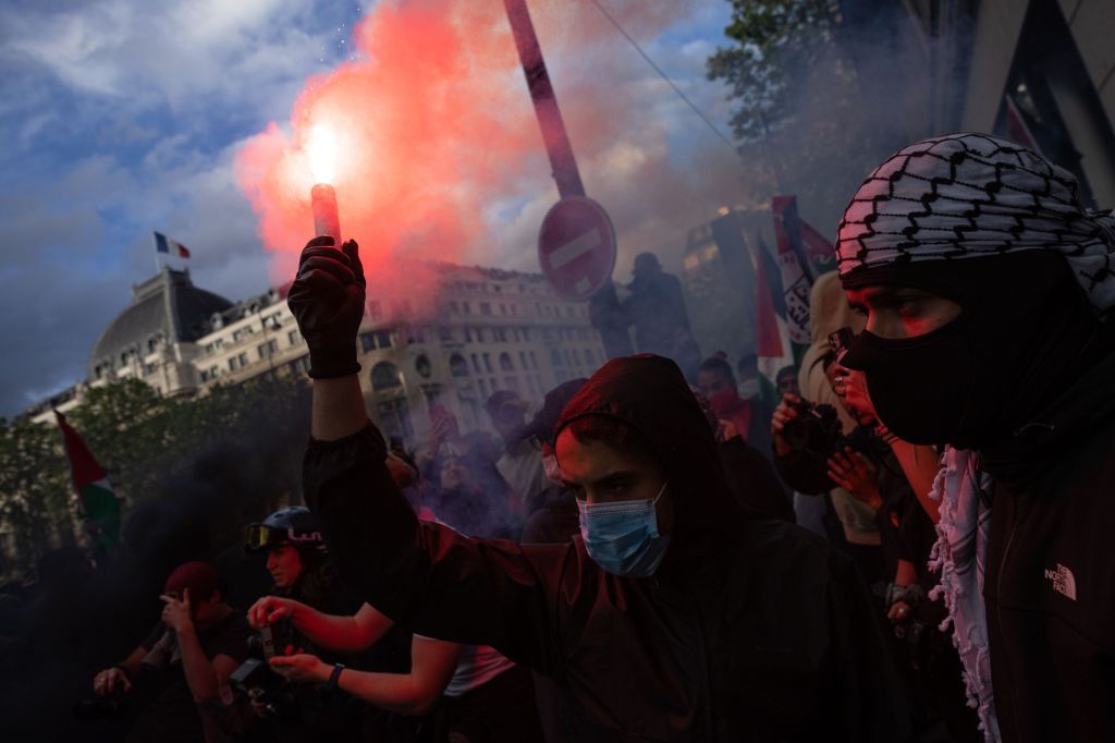 Pro-Palestinian activists holding a flare during a demonstration in central Paris, responding to Israel's recent bombing of Rafah in Gaza