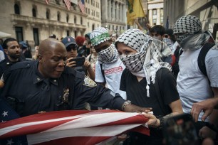 A Pro-Palestinian protester tries to grab an American flag from Pro-Israel supporters as a police officer tries to interfere during a demonstration.