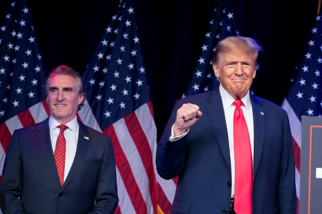 Donald Trump arrives to speak at a caucus night rally in Las Vegas, Feb. 8, 2024, as North Dakota Gov. Doug Burgum watches. 