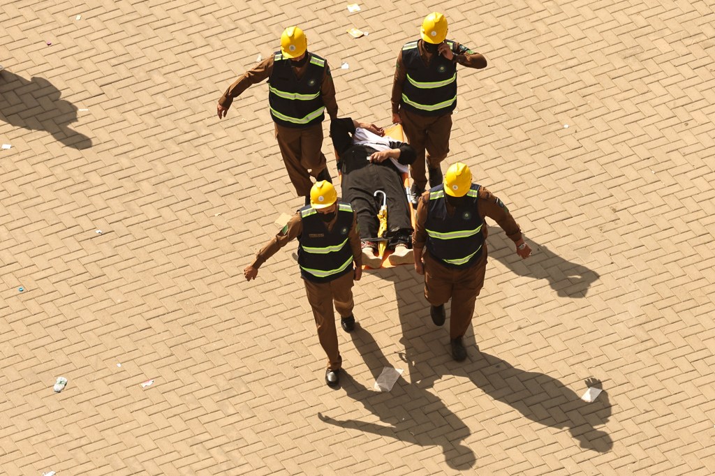 Rescuers carry away a man on a stretcher under the punishing sun. 