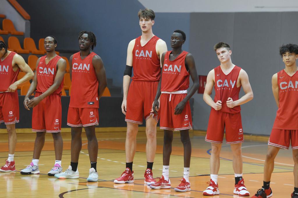 17-year-old Canadian basketball player Olivier Rioux, the world's tallest teenager at 231 centimeters (7'3), participating in a tournament on a basketball court with other players in red uniforms