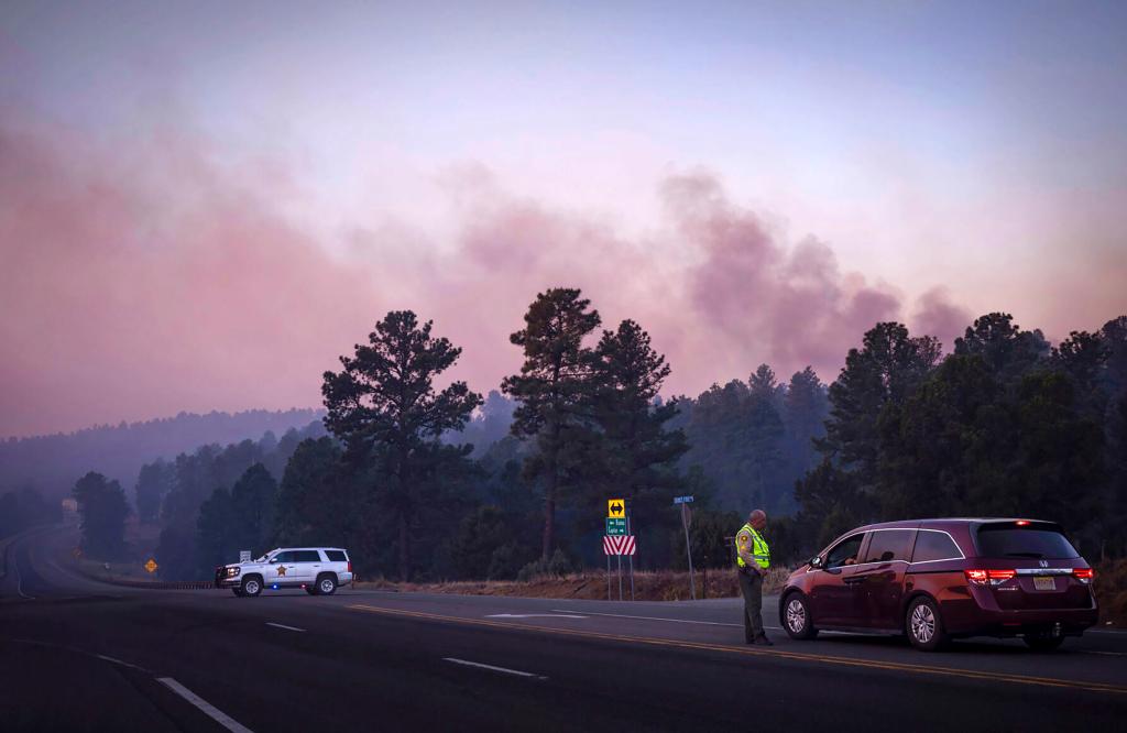 Smoke rising from the forest as police officers turn drivers away near Ruidoso.