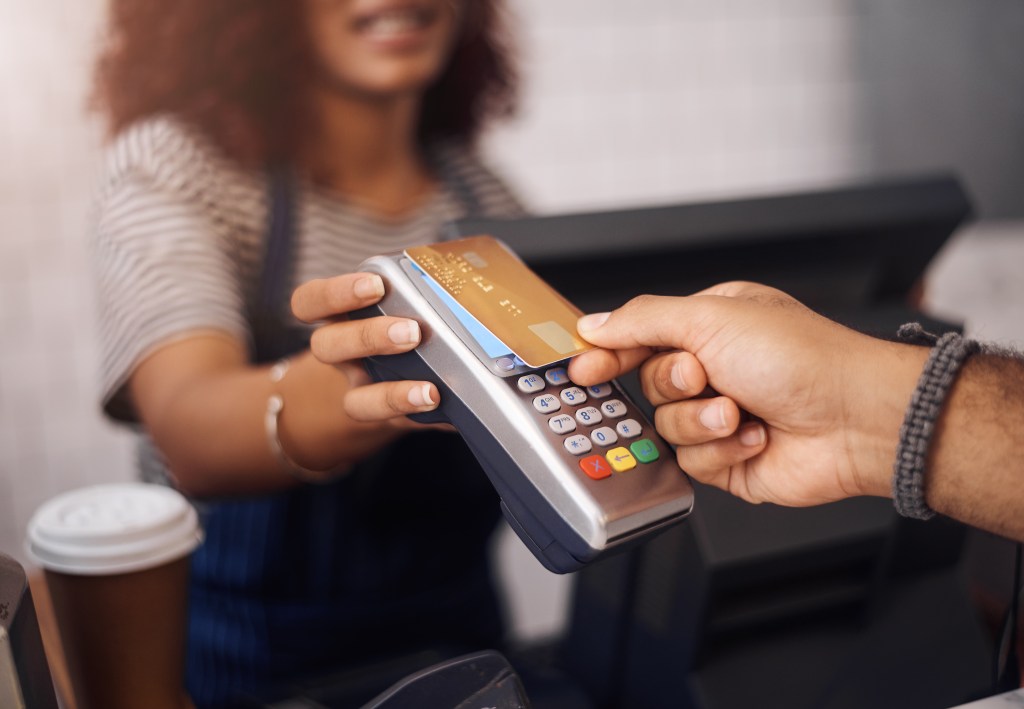 Customer making a contactless payment with a credit card at a cafe cashier using an NFC-enabled point of sale machine