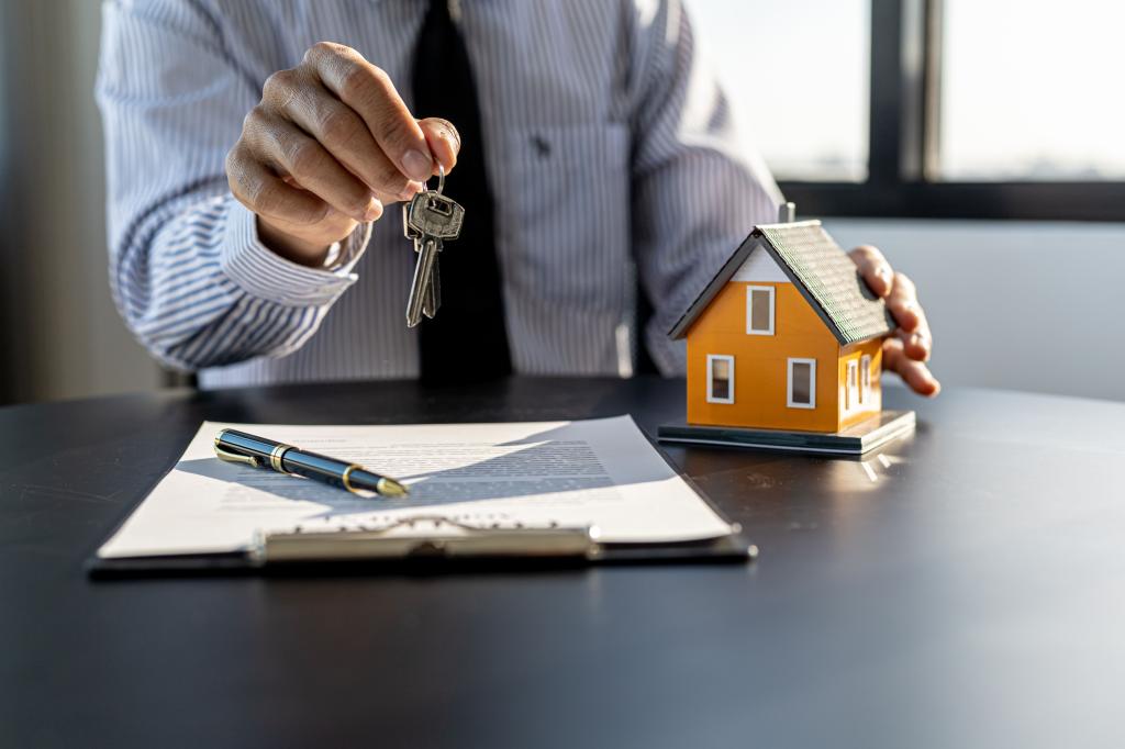 A home rental company employee is handing the house keys to a customer.