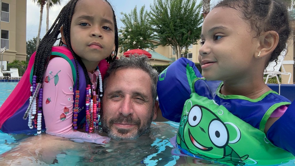 Ari Nagel takes a selfie with two little girls inside a pool