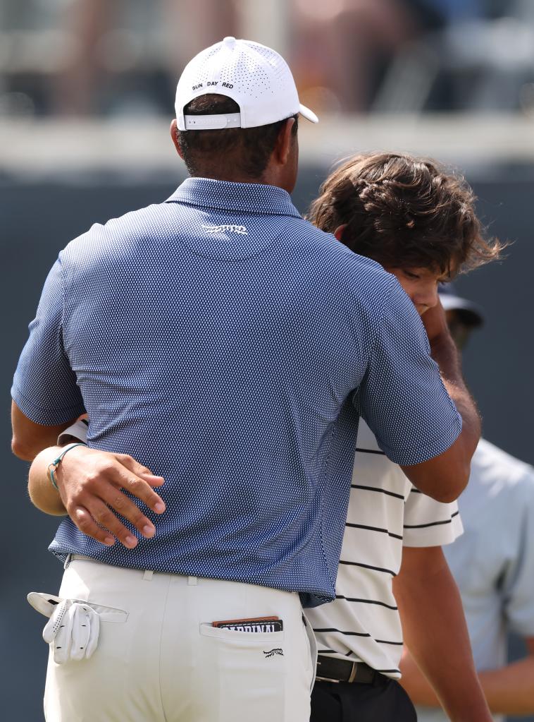 Tiger Woods hugs his son Charlie on the 18th green on Monday.