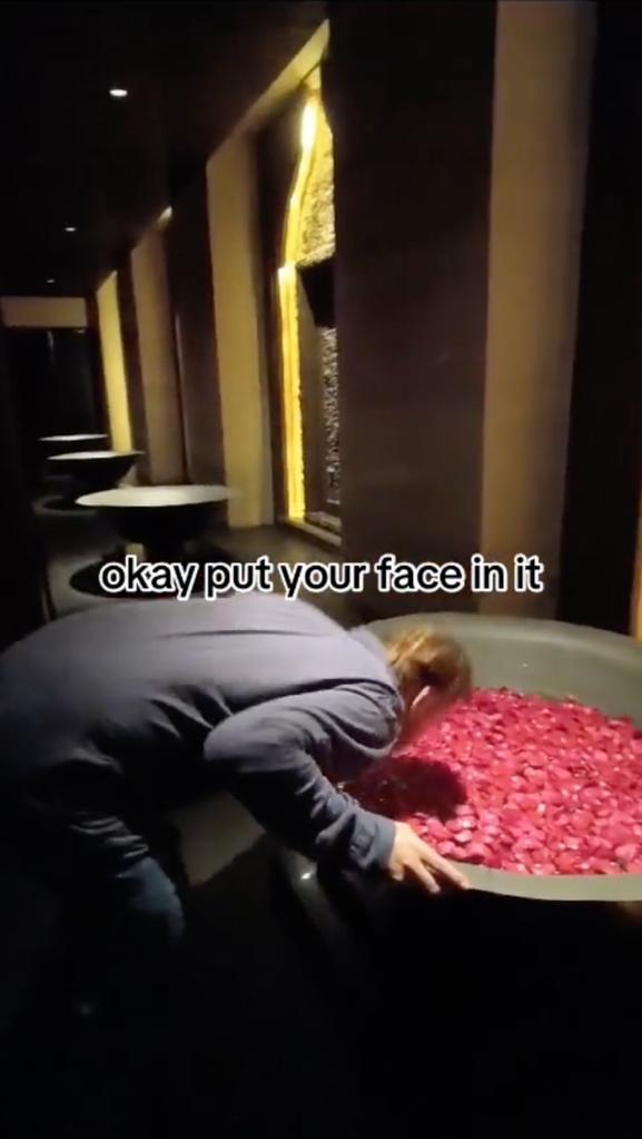 Tourist making an embarrassing stunt in a decorative bowl of water filled with red petals at the Apurva Kempinski Hotel in Bali