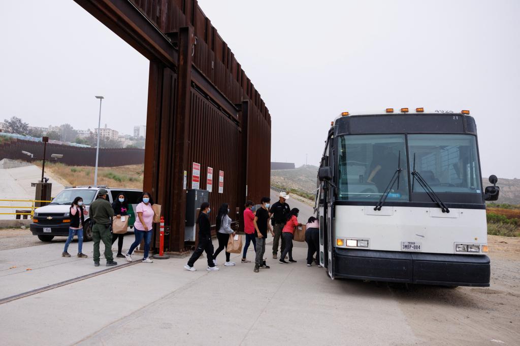 U.S. Border Patrol agents transporting migrants between border walls in San Diego, California, under new immigration restrictions