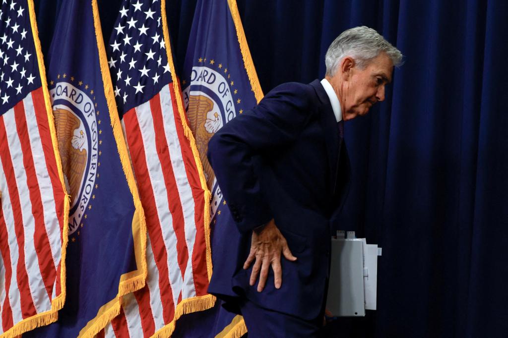 U.S. Federal Reserve Chair Jerome Powell speaking during a press conference in Washington, with flags in the background.