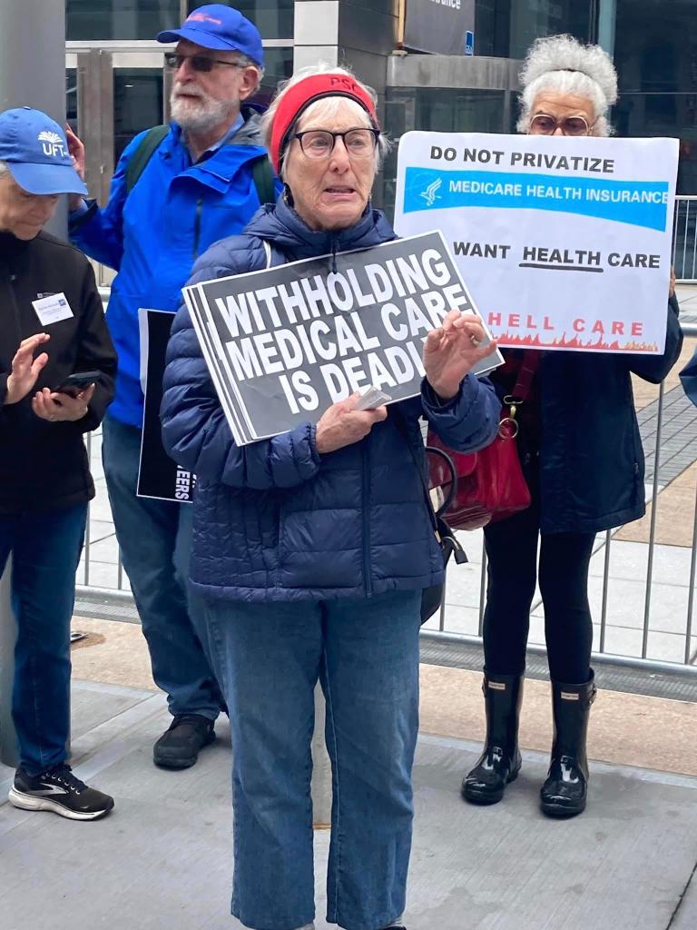 George P. Smith amidst UFT retirees protesting over Medicare coverage, a woman holding a sign.