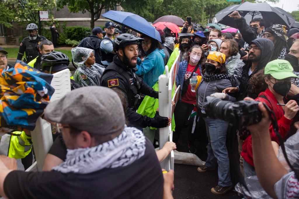 University of Chicago Police officer yelling at pro-Palestinian protesters trying to break through a barrier during a rally, with students in crowd