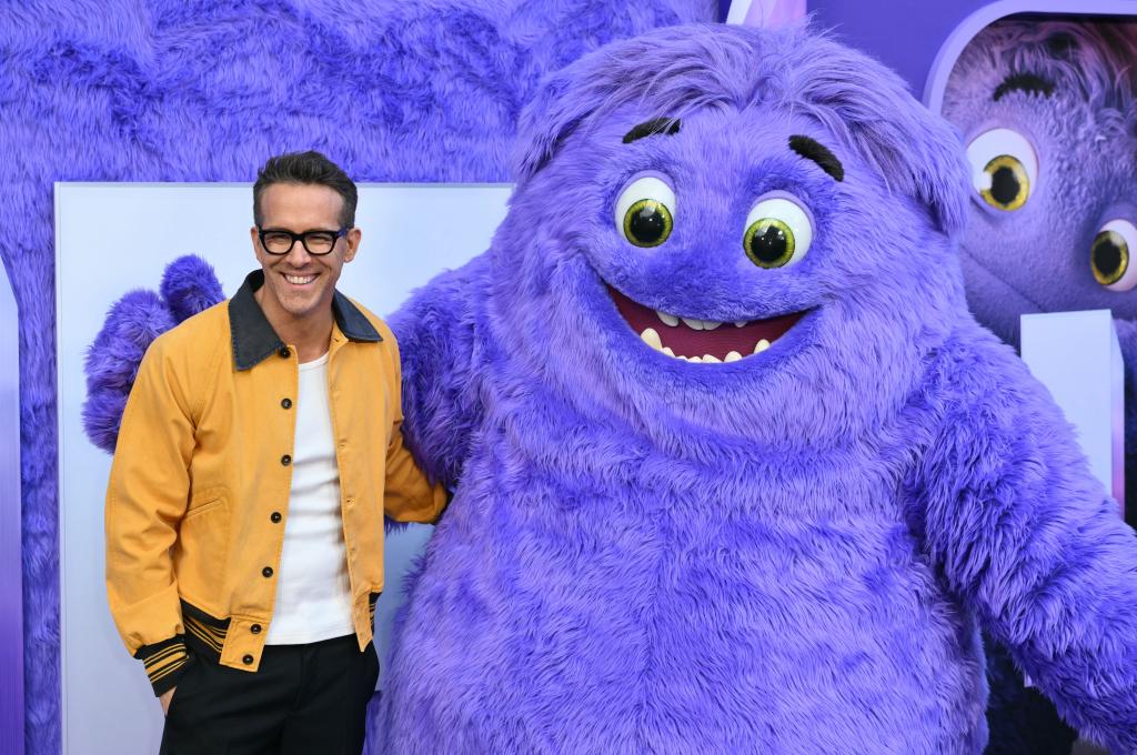 Ryan Reynolds smiling with a purple monster. 