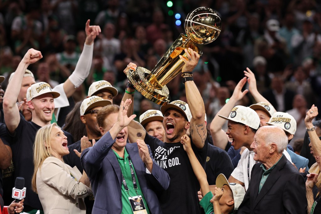 Head coach Joe Mazzulla of the Boston Celtics lifting the Larry O’Brien Championship Trophy after a win in the 2024 NBA Finals game