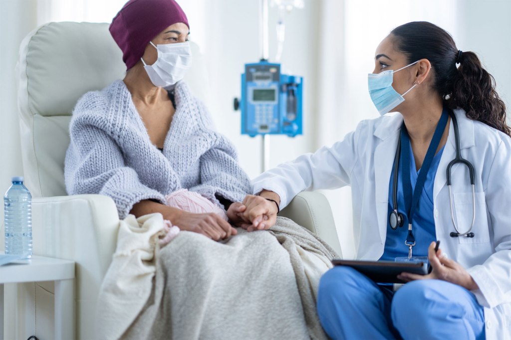 A woman in a hospital gown with a doctor holding her hand, symbolizing the greater cancer risk among the wealthy