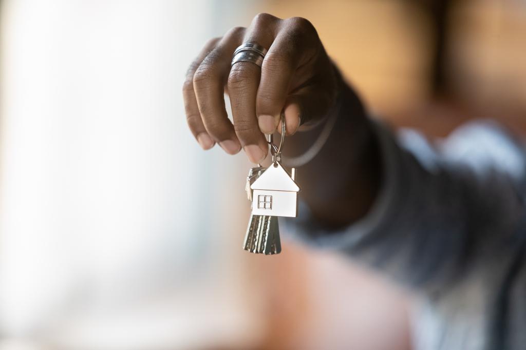 Young African American realtor handing over a set of keys to a new home