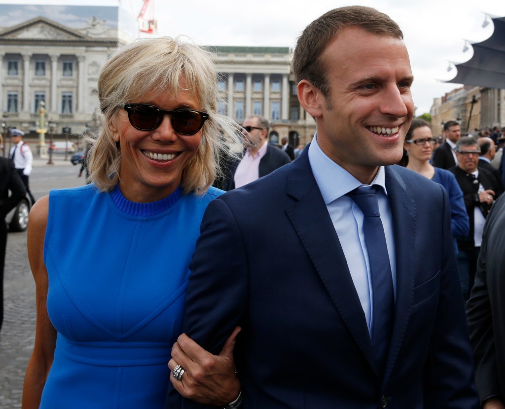 Emmanuel Macron and his wife Brigitte Trogneux smiling as they arrive at the Bastille Day military parade in Paris, France