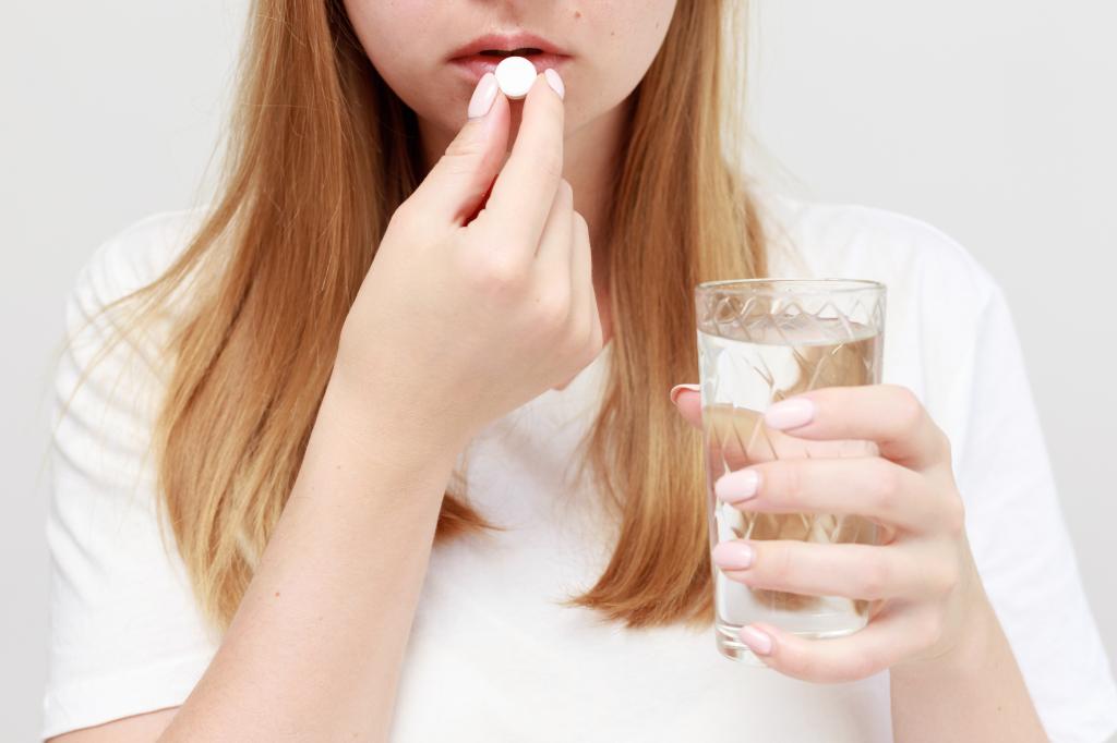woman eats a pill with a glass water. close-up