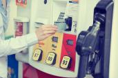 A woman's hand swiping a credit card at a gas pump station