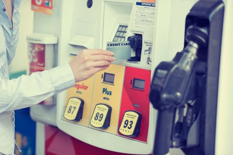 A woman's hand swiping a credit card at a gas pump station
